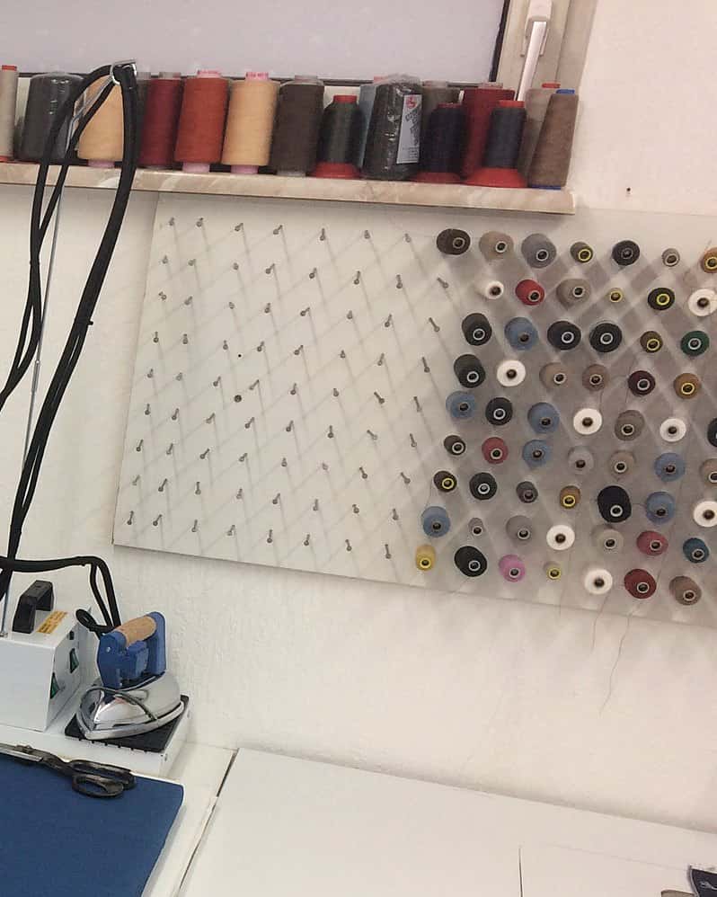 Werkstatt mit Garnregal und Garnwand, links unten die Dampfbügelstation mit Bügeleisen und Schere
